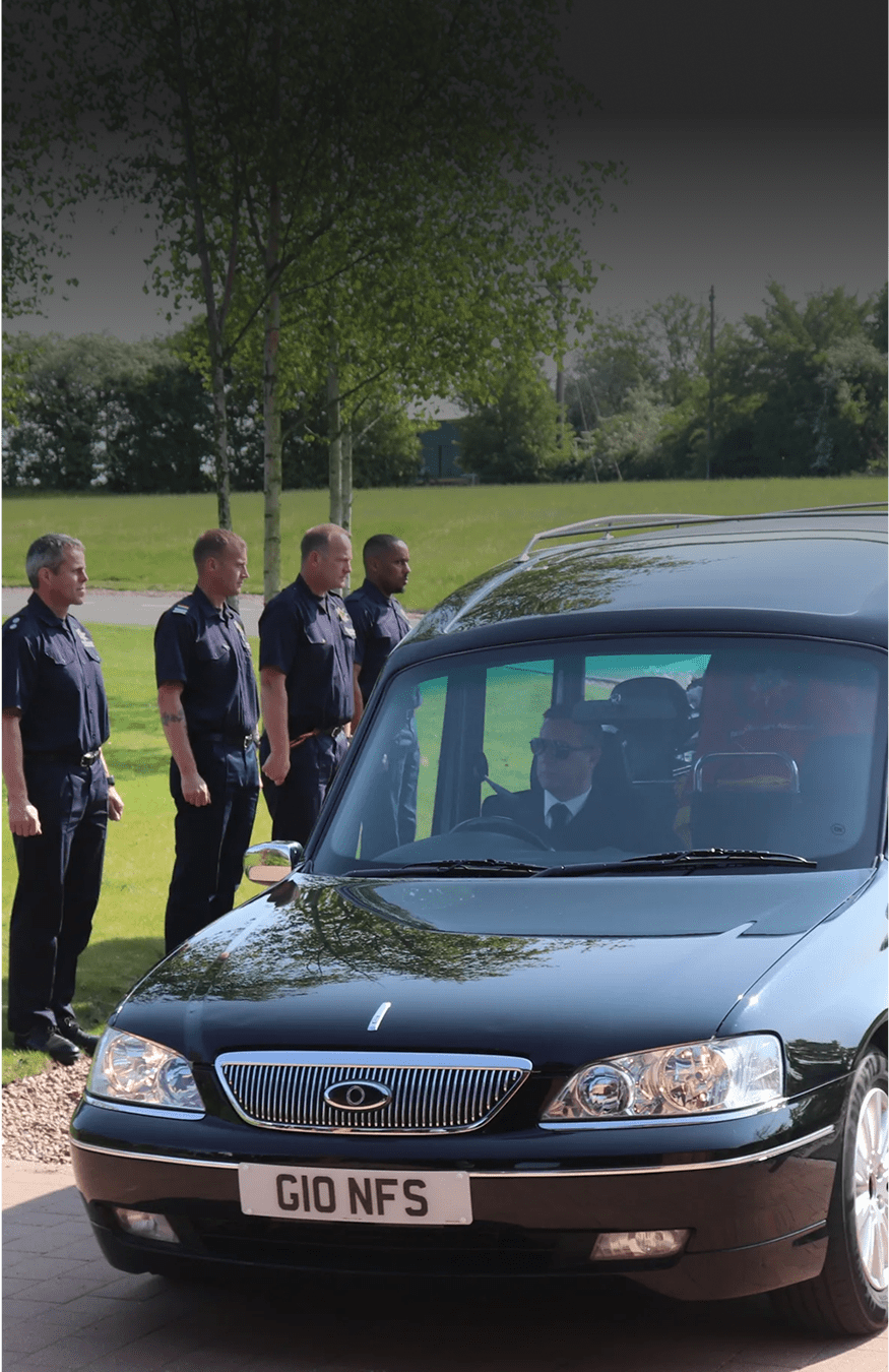 Hearse with pallbearers in background