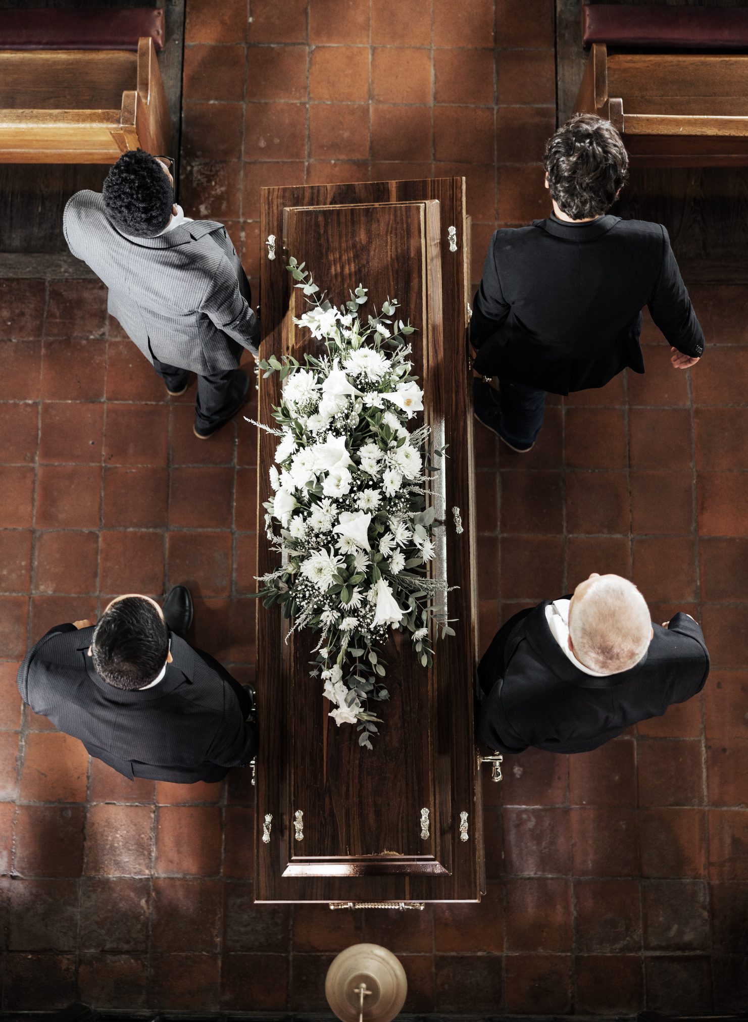 Pallbearers carrying a flower-adorned coffin.