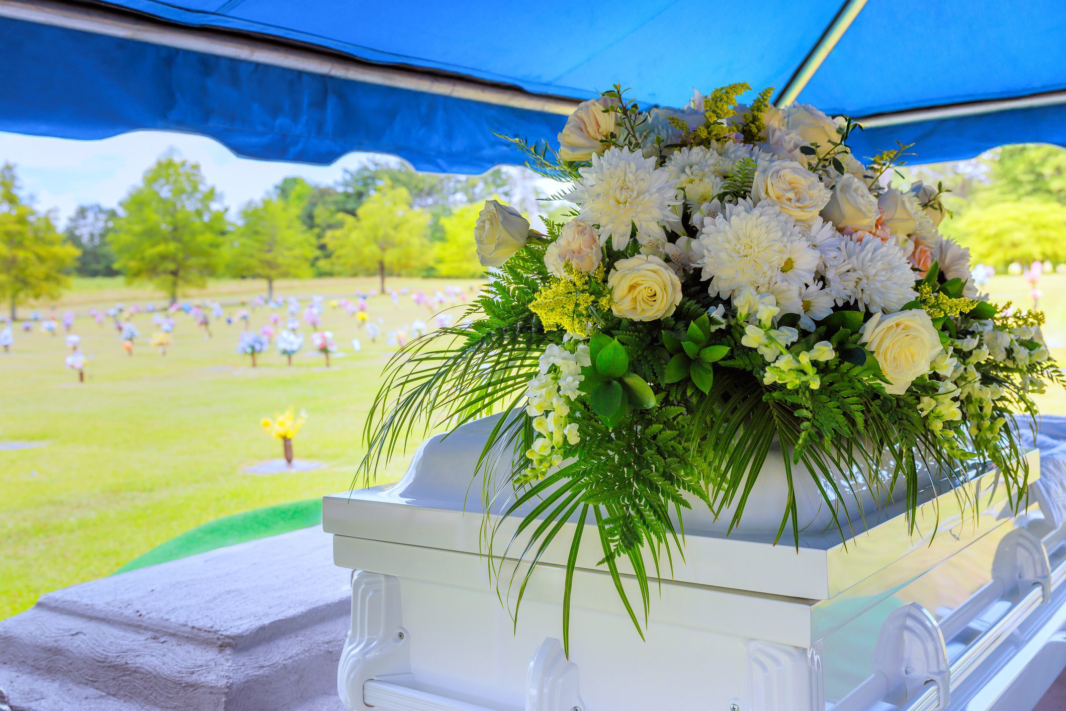 White casket with flowers in cemetery.
